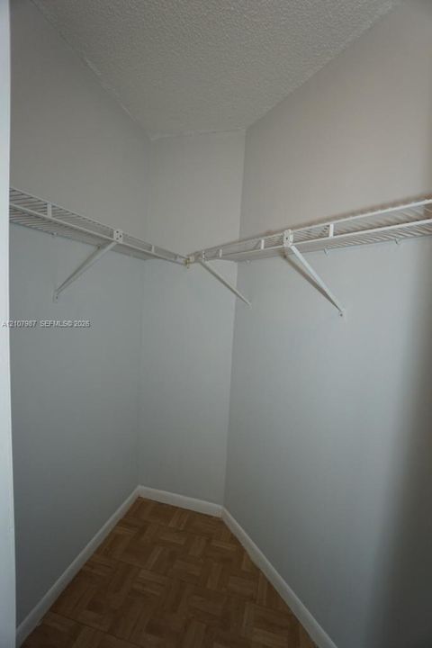 Storage space featuring white wire shelving and wood-finish parquet flooring