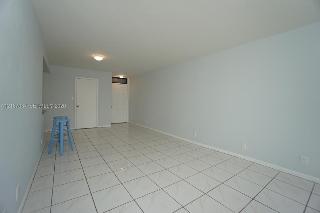 Neutral-toned interior space featuring light-colored square tile flooring and flush-mount ceiling lighting