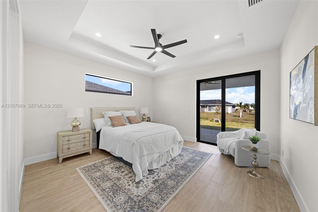 Tray ceiling with recessed lighting, wood-finish flooring, matte black ceiling fan, horizontal clerestory window, and black-framed sliding glass doors