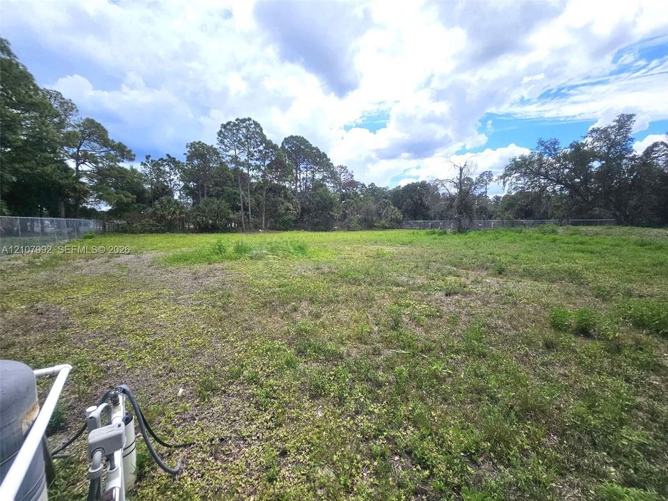 Expansive parcel of land featuring chain-link perimeter fencing and mature tree coverage