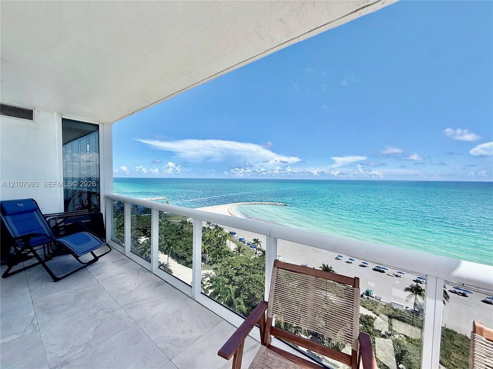 Covered balcony featuring large-format stone flooring and glass panel railing