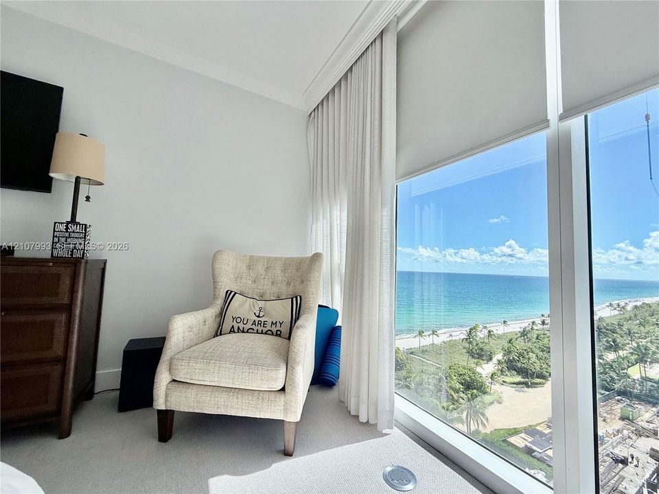 Floor-to-ceiling windows featuring automated roller shades, crown molding, and ocean scenery