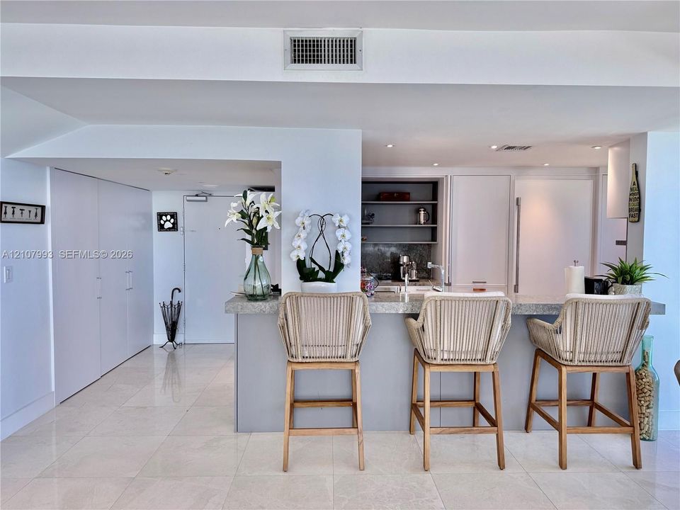 Kitchen featuring a stone-topped breakfast bar, recessed ceiling lighting, built-in cabinetry, and tile flooring