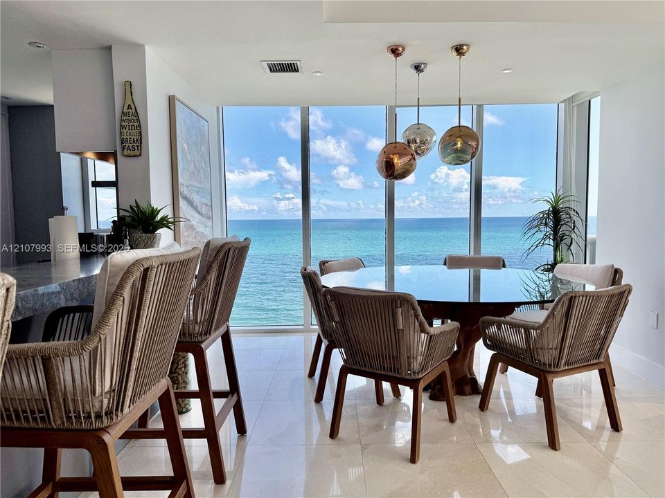 Floor-to-ceiling windows with ocean backdrop, polished stone flooring, and trio of spherical pendant light fixtures