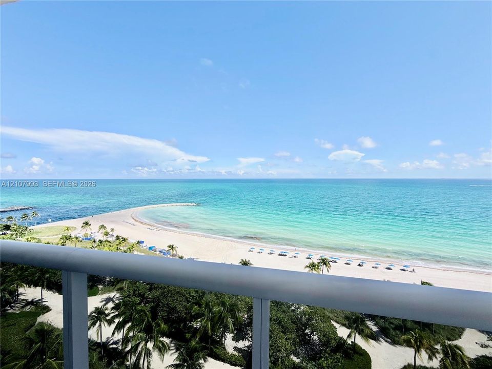 Private balcony with a metal railing overlooking the oceanfront and sandy beach