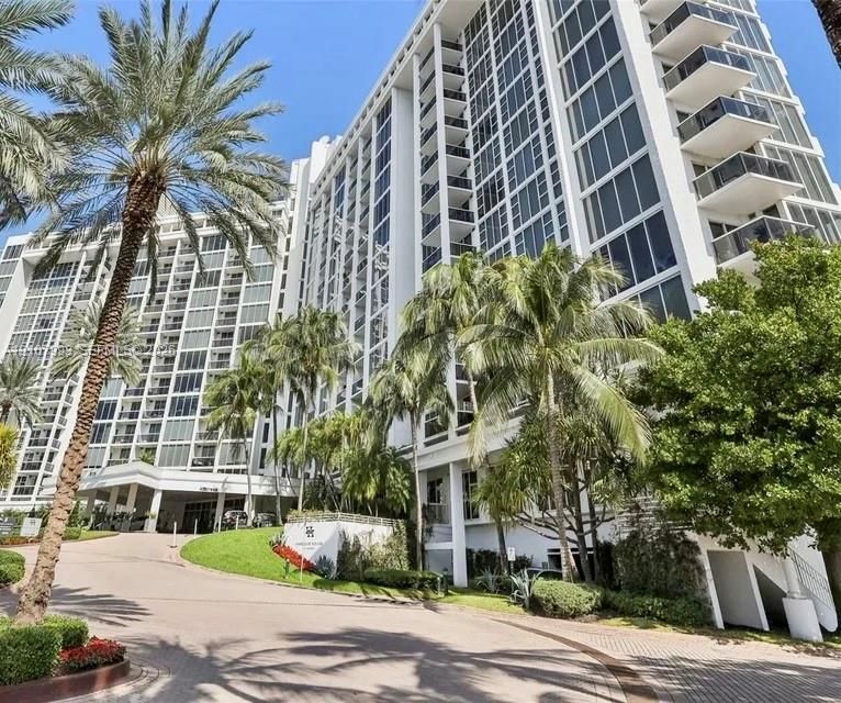 High-rise architectural exterior featuring glass curtain walls, private balconies, a porte-cochère entry, and mature landscaping