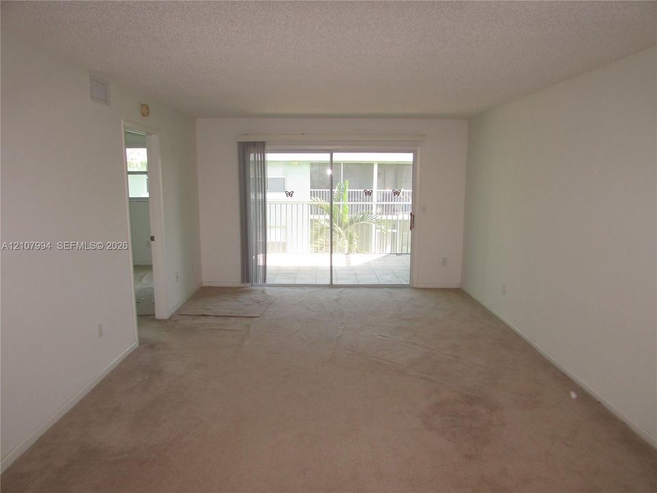 Neutral-toned carpeting and sliding glass doors providing outdoor access