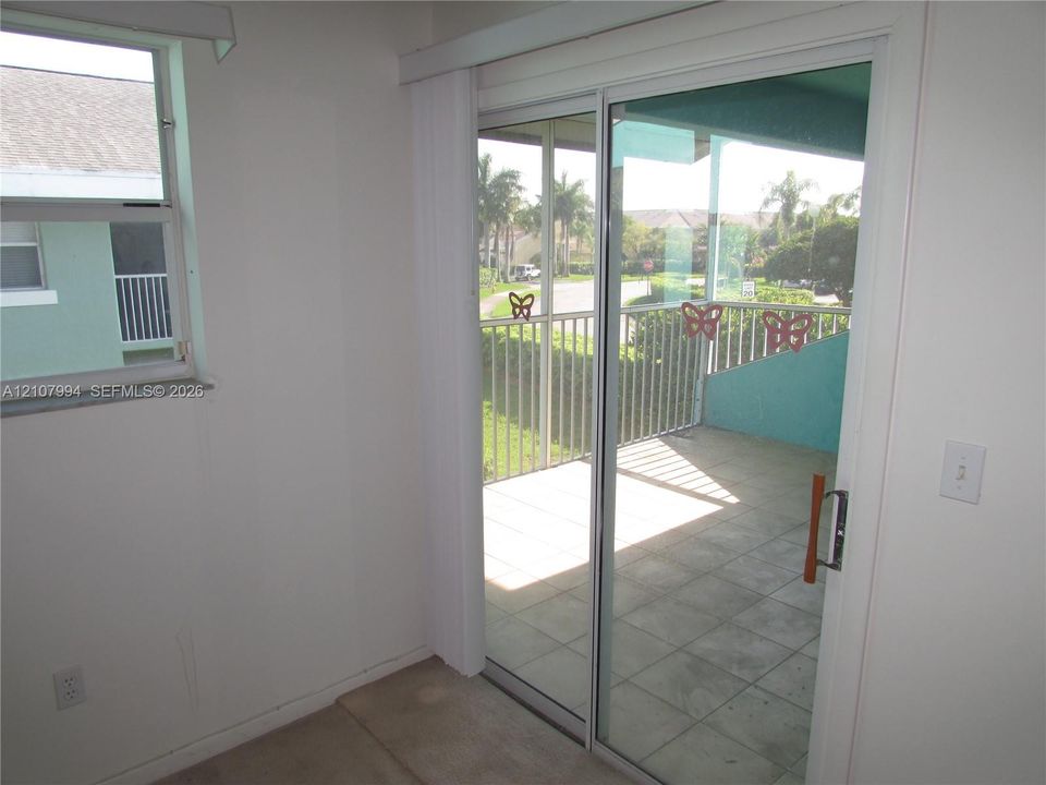 Sliding glass patio door, single-hung window, and private balcony featuring metal railing and tile flooring