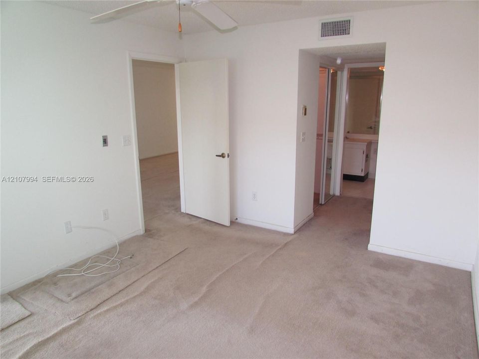 Neutral-toned carpeting, ceiling-mounted paddle fan, and white interior doors
