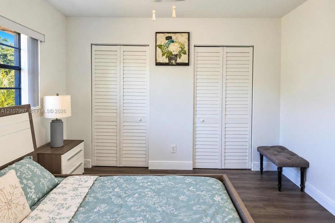 Third bedroom Large floor-to-ceiling windows with dark framing, wood-finish flooring, and a ceiling fan with integrated lighting