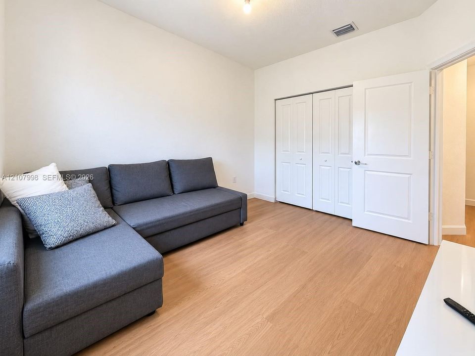 Interior room featuring wood-finish flooring, double-panel closet doors, and a solid-core interior door with satin nickel hardware