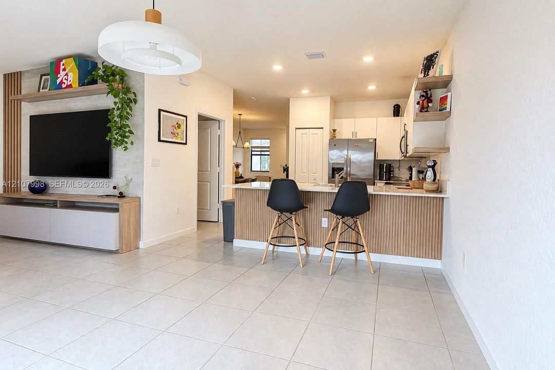 Kitchen featuring white cabinetry, a built-in wood-slat peninsula, integrated floating shelving, and tile flooring