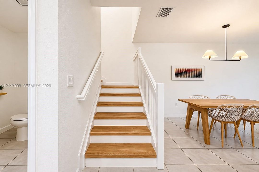 Staircase featuring wood-finish treads, white risers, and a painted wood balustrade