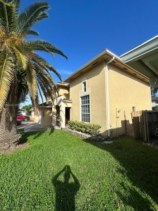 Stucco exterior featuring a multi-story layout, tall rectangular window, concrete driveway, and mature palm tree