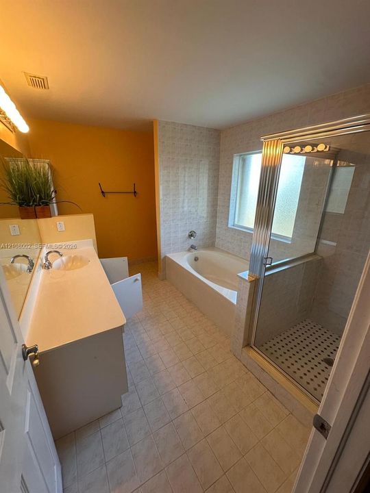Bathroom featuring a vanity with integrated sink, a tiled alcove soaking tub, and a separate glass-enclosed shower with patterned tile flooring