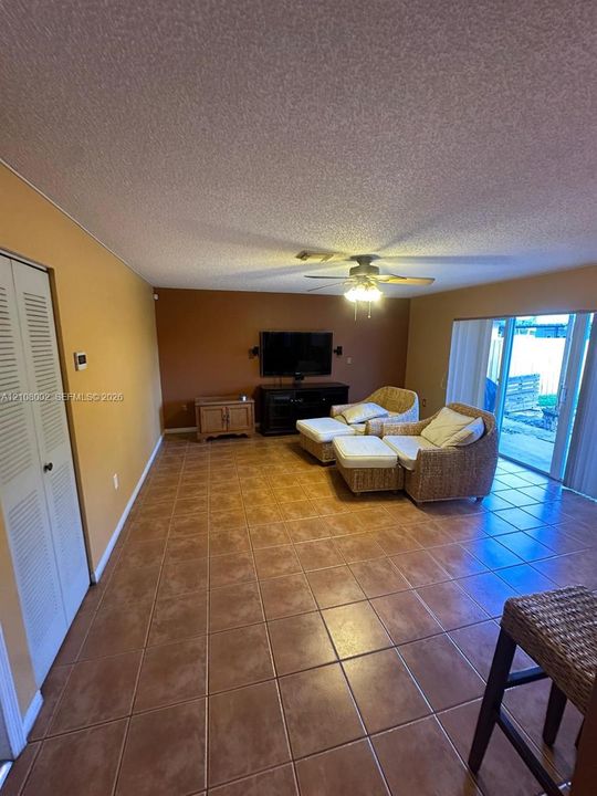 Ceramic tile flooring, louvered bi-fold closet doors, ceiling fan with integrated light fixture, and sliding glass door