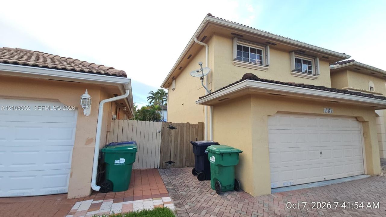 Stucco exterior featuring dual two-car garages, tile roofing, and paver driveway