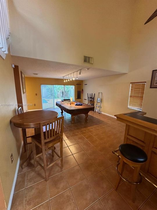 Vaulted ceilings, large-format ceramic tile flooring, built-in bar, track lighting, and sliding glass doors