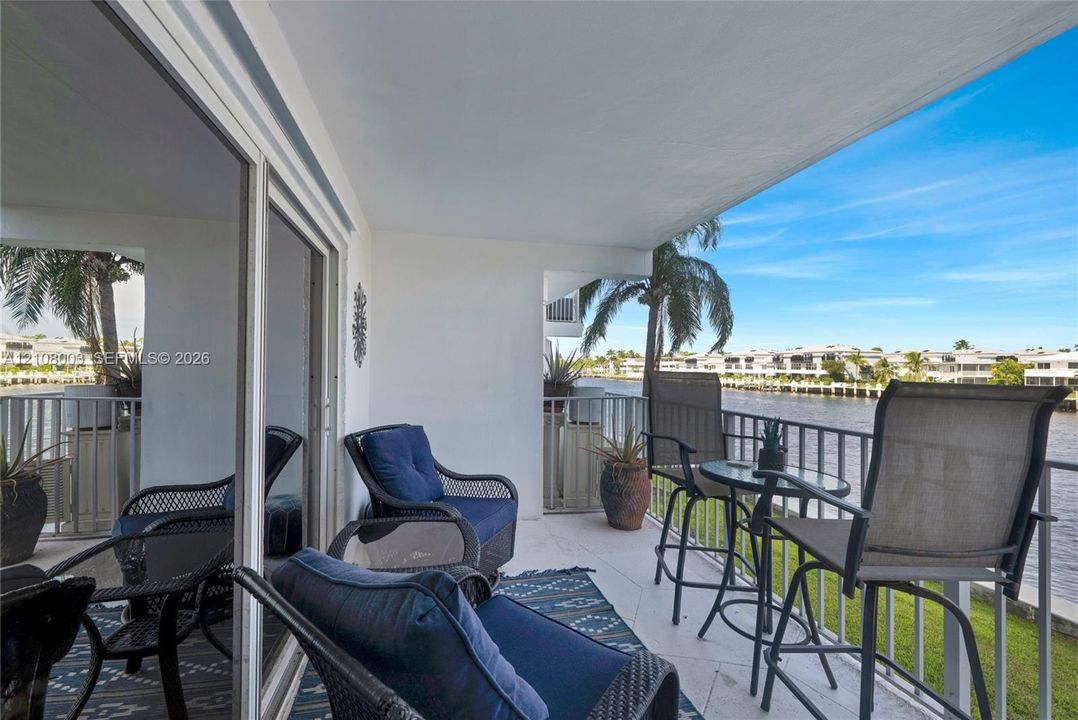 Covered balcony featuring tiled flooring, metal railing, and direct water exposure