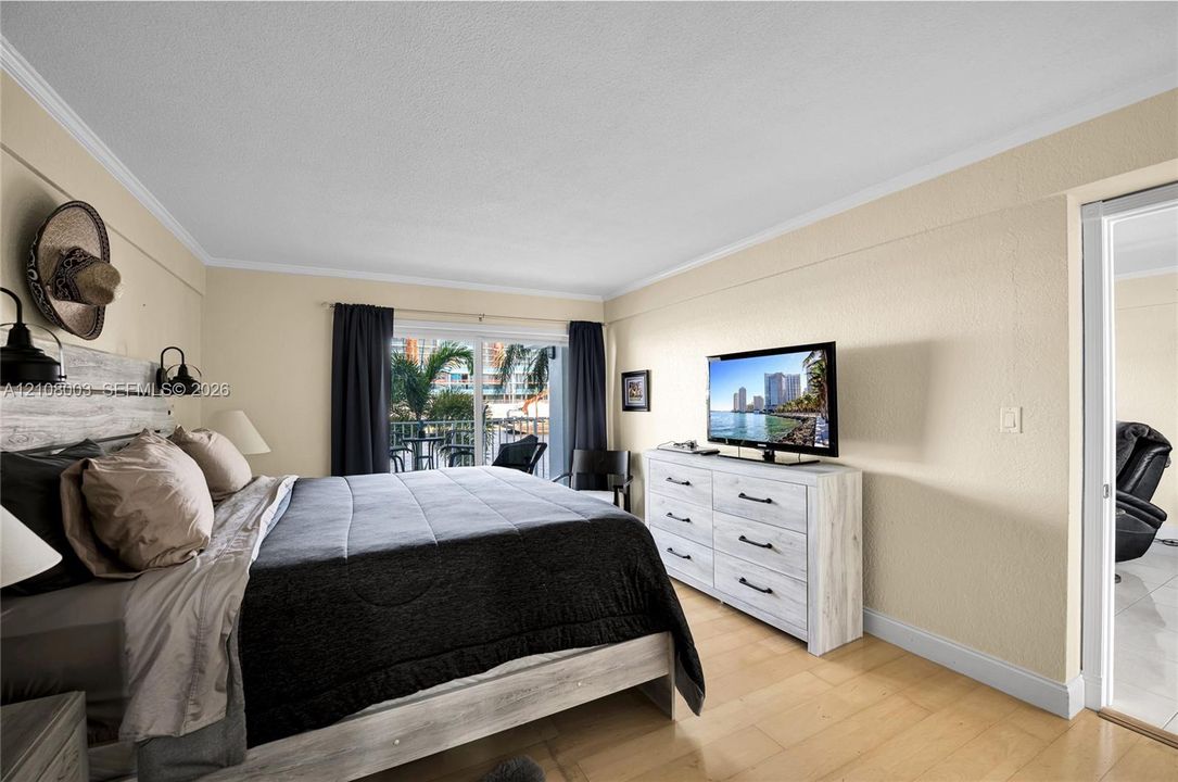 Light-filled room featuring wood-finish flooring, sliding glass doors, and dual wall-mounted light fixtures