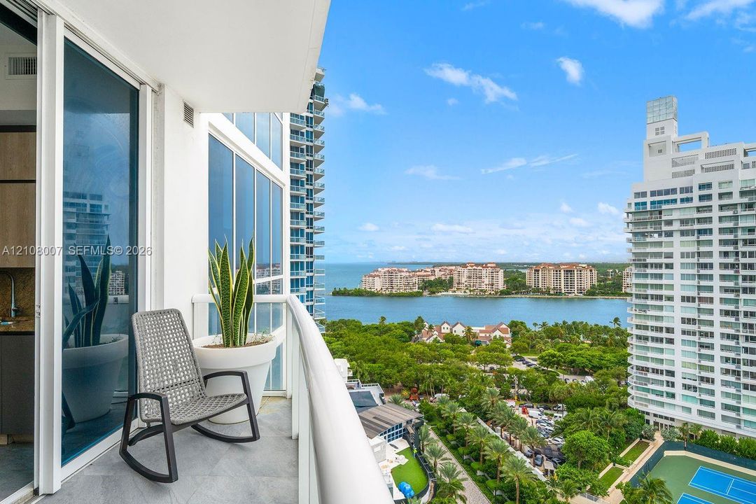 Private balcony with glass railing, stone-finish flooring, and floor-to-ceiling sliding glass doors