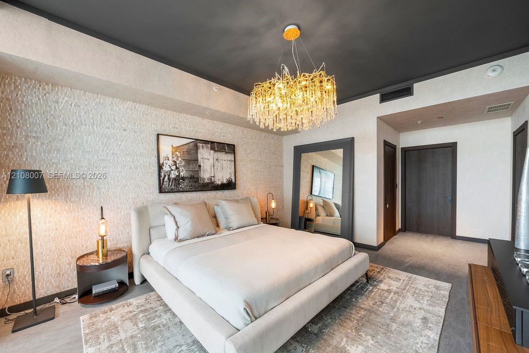 Textured stone feature wall with a contrasting dark ceiling, statement multi-tiered crystal chandelier, and dark-finish paneled interior doors