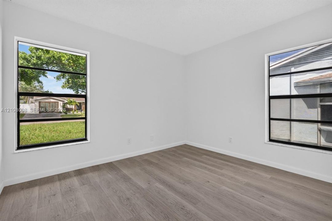 Neutral-toned interior room featuring wood-finish flooring and dual horizontal sliding windows with black frames