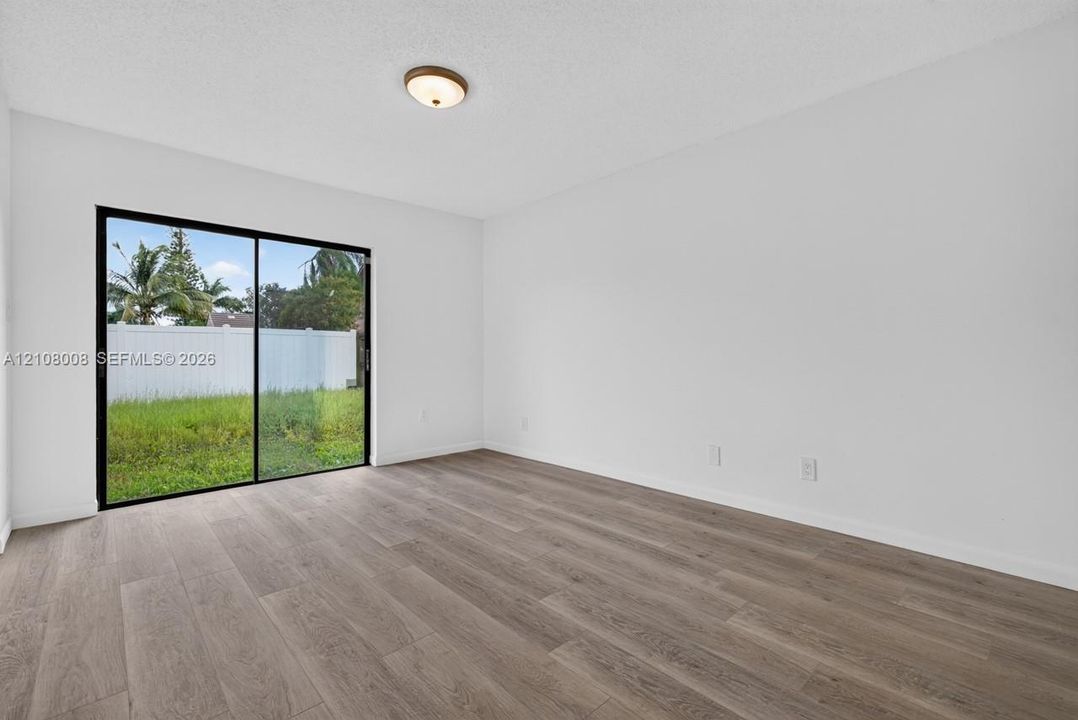 Interior space featuring wood-finish flooring, white walls, and a glass sliding door