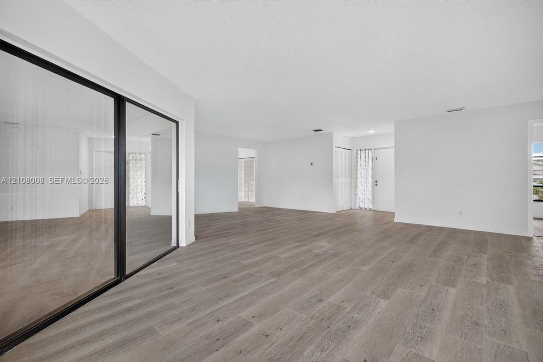 Interior space featuring wood-finish flooring, floor-to-ceiling sliding glass doors with black frames, and recessed lighting