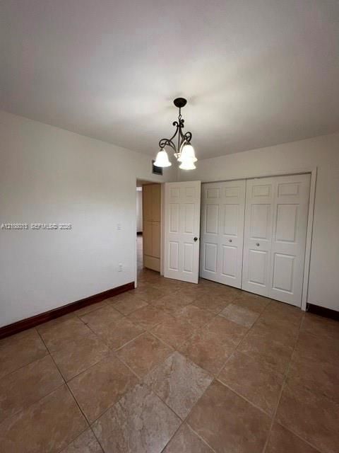 Ceramic tile flooring, multi-panel closet doors, decorative iron-finish light fixture, and interior doors with integrated hardware