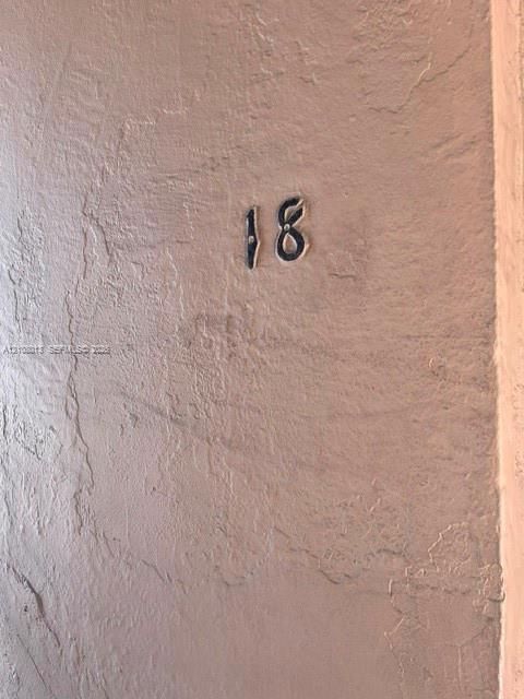Textured neutral-toned wall finish with mounted metal address numerals