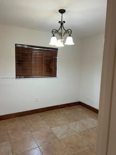 Neutral-toned tile flooring, dark wood-finish window blinds, and a traditional-style multi-light chandelier
