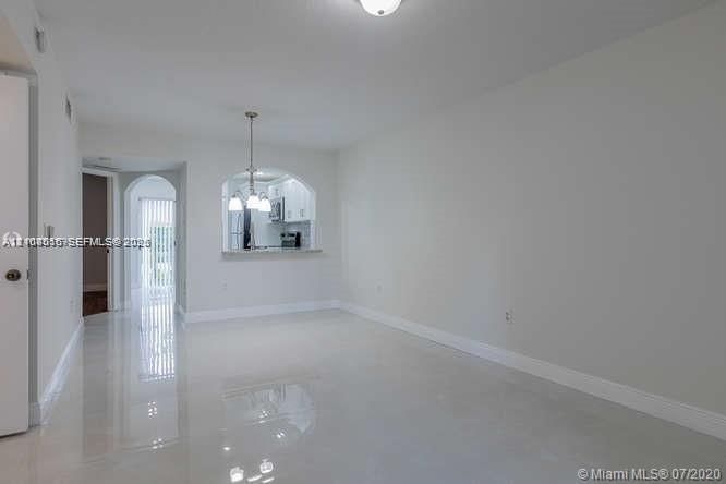 Open interior space featuring polished tile flooring, arched wall cut-out, and a suspended multi-light fixture