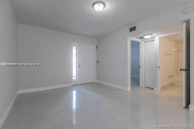 Neutral-toned interior featuring glossy tile flooring, recessed and flush-mount lighting, a six-panel exterior door with sidelight, and a walk-in closet with six-panel double doors