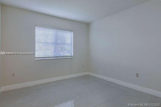 Neutral interior space featuring polished tile flooring, light-toned wall finishes, and a single window with horizontal blinds