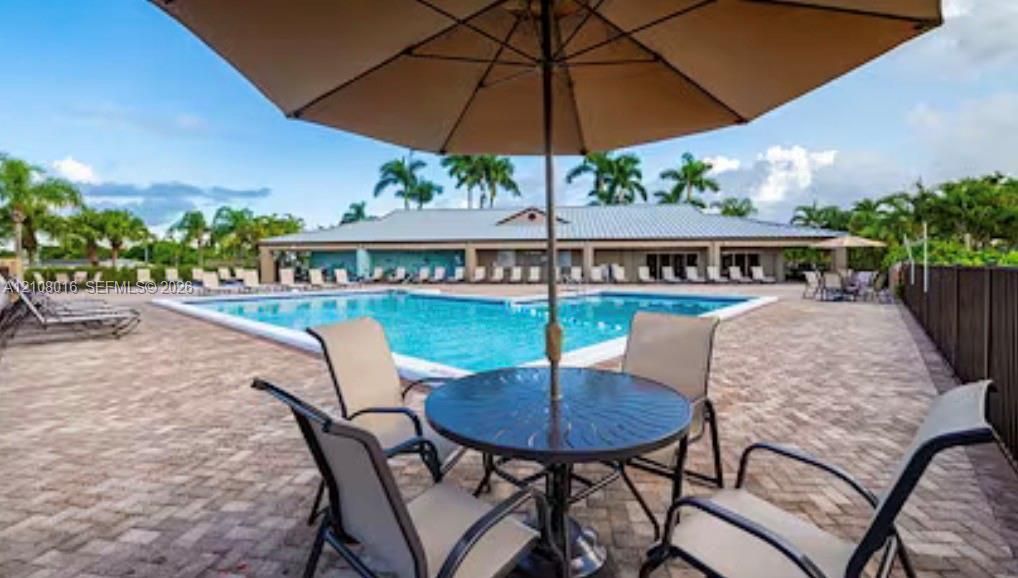 Swimming pool with a brick-paver deck, metal-roof clubhouse, and perimeter fencing