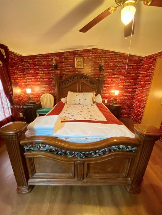 Interior space featuring red brick-patterned walls, wood-finish flooring, and a ceiling-mounted light fixture with integrated fan