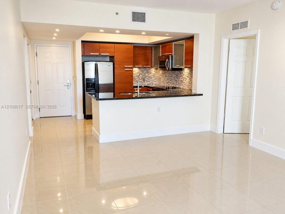 Kitchen featuring stained wood cabinetry, stone countertops, stainless steel appliances, mosaic tile backsplash, and recessed lighting