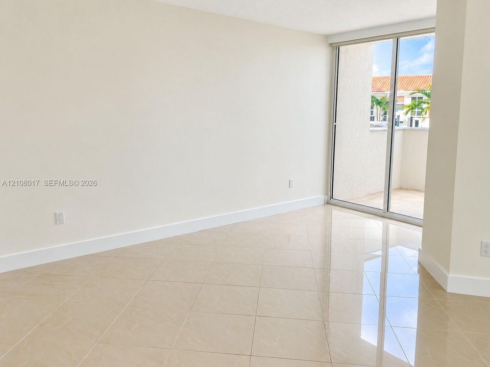Neutral-toned interior featuring large-format polished tile flooring and floor-to-ceiling sliding glass doors opening to an exterior balcony