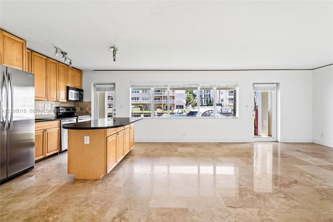 Kitchen featuring natural wood cabinetry, polished stone flooring, a center island with a stone countertop, and stainless steel appliances