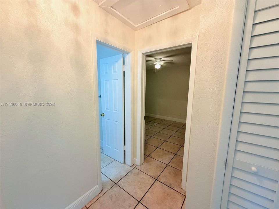 Hallway featuring ceramic tile flooring, six-panel interior doors, and louvered closet doors
