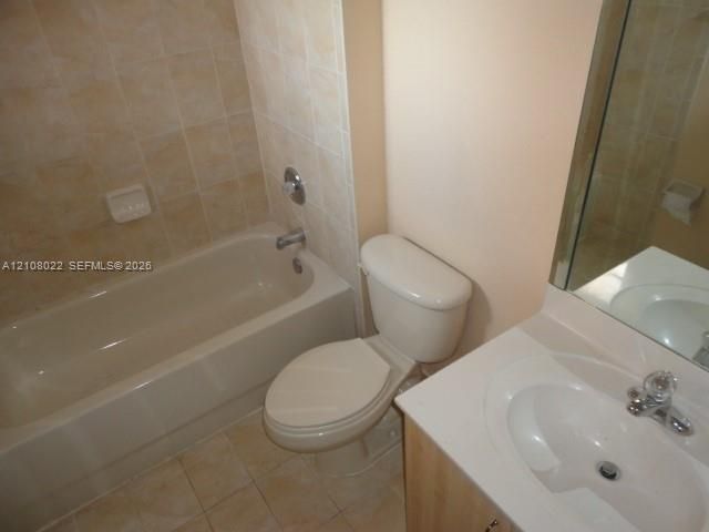 Bathroom featuring a vanity with a white countertop and integrated sink, a bathtub with tile surround, and a wall-mounted mirror