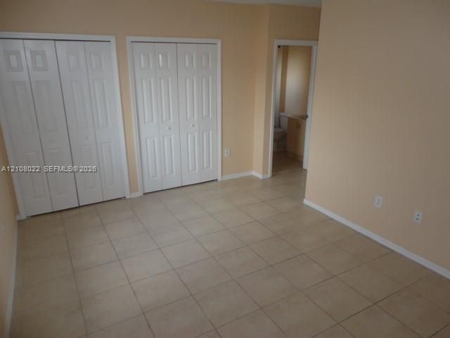 Ceramic tile flooring, two sets of white paneled bifold closet doors, and neutral wall paint