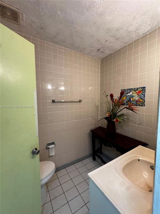 Ceramic tile wall finishes, integrated vanity with recessed basin, and metal hardware fixtures