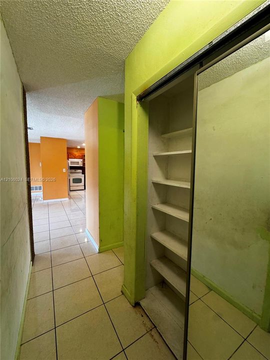 Hallway featuring tile flooring, sliding mirrored closet doors, and built-in shelving