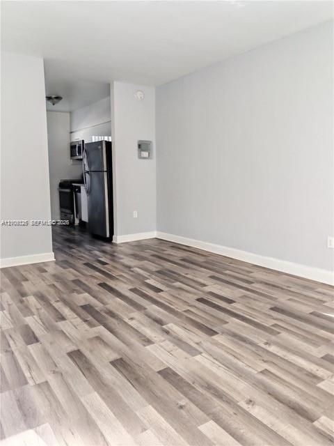 Wood-finish flooring throughout, stainless steel refrigerator, and integrated stainless steel cooking range