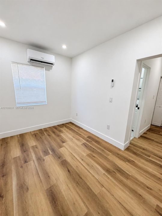 Room featuring wood-finish flooring, recessed lighting, and a wall-mounted ductless mini-split HVAC unit