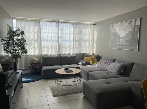 Living area featuring large-format ceramic tile flooring and floor-to-ceiling windows