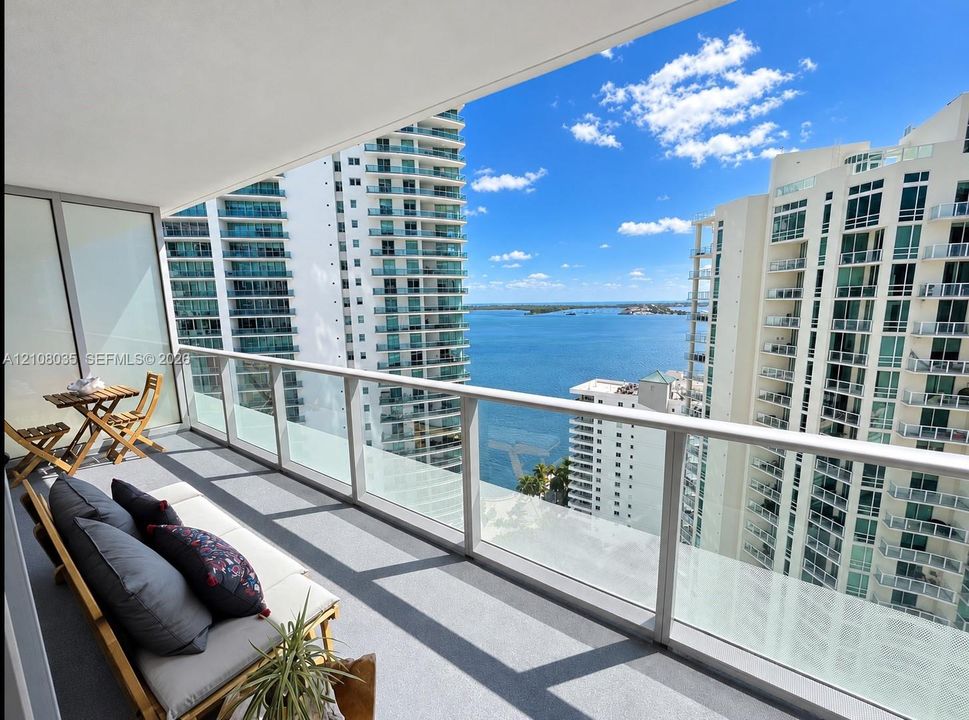 Private balcony featuring a glass-panel railing, concrete flooring, and water scenery