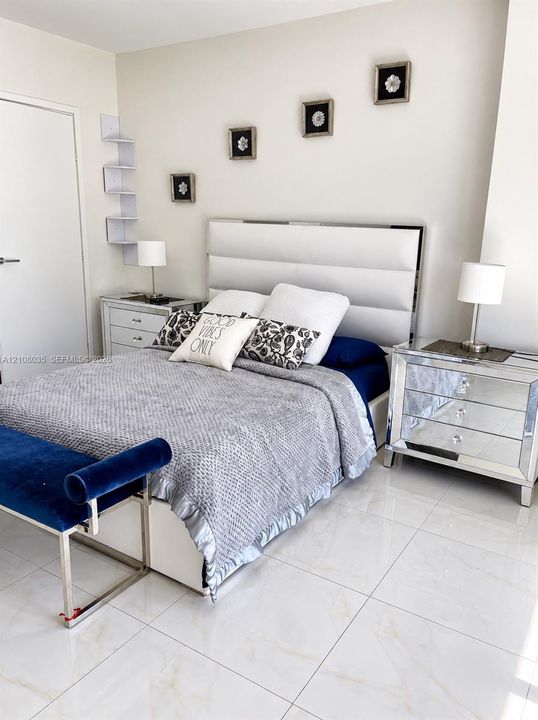 Large-format polished tile flooring featuring subtle neutral veining and wall-mounted white corner shelving